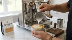 A home barista pouring velvety microfoam milk to create a rosetta design, brewed using a high end home espresso machine.