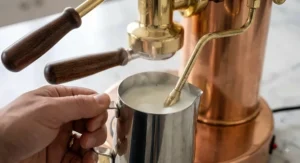 Steaming milk in a stainless steel pitcher using the steam wand of an Elektra Microcasa Leva machine