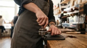 A pair of hands tamping coffee grounds before using a heat exchange espresso machine for small households.