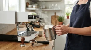 A person using the steam wand on a thermoblock espresso machine to froth milk for a cappuccino.